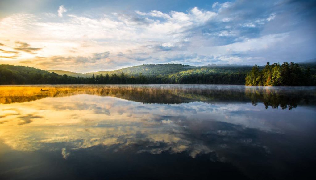 image of morning sun over a lake view scene with sun hitting the distance landscape