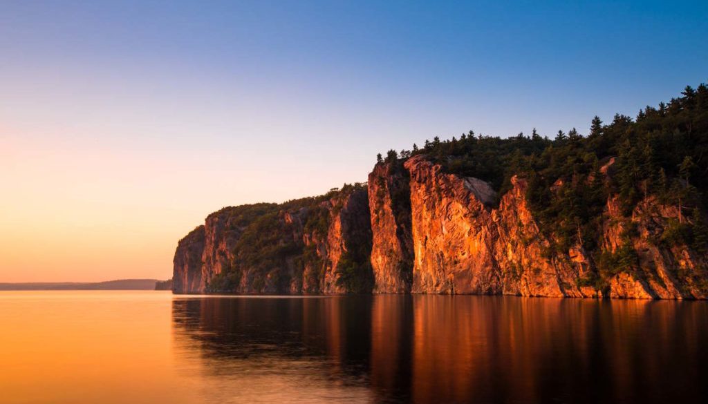 Image of Mazinaw Rock at Sunset showing cliff face in the colour of red