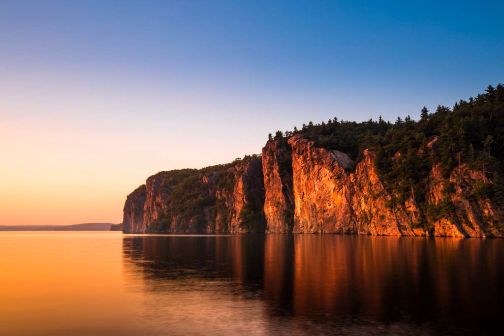 Image of Mazinaw Rock at Sunset showing cliff face in the colour of red